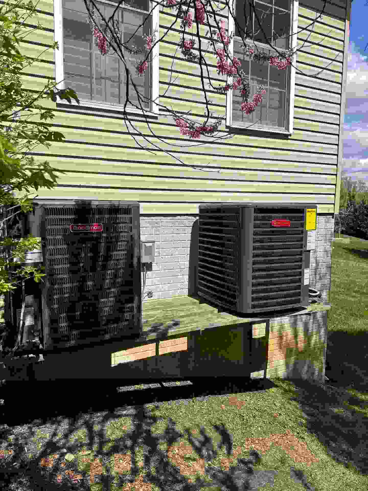 Blog Technician cleaning a spring HVAC unit outside a Baltimore home